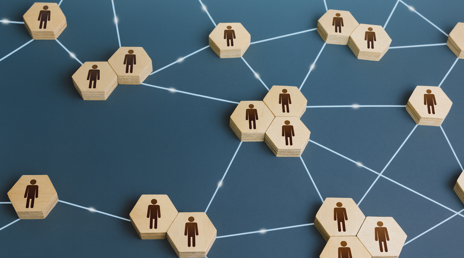 Blocos hexagonais de madeira com ícones de pessoas conectados por linhas sobre fundo azul, simbolizando ações coletivas.